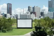 広大な芝生に設置された巨大スクリーンで映画を楽しむ