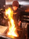 「名物 地鶏のもも焼き」を調理中のスタッフ