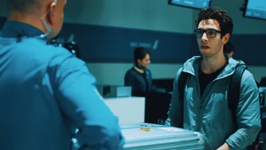 荷物検査に引っ掛かり焦りの表情を浮かべる乗客