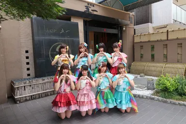 活動拠点の寿司店の前で。メンバーは8人