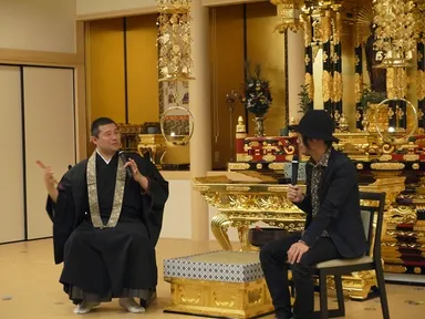 散華でまいた紙製の花びらが残る本堂で対談する住職(左)と松本氏(右)