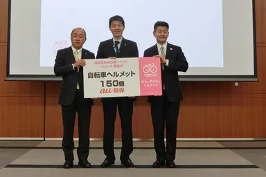 【ヘルメット贈呈式】左から、au損保　伊東専務、キヤノン　田原ヒューマンリレーションズ推進センター部長、東京都 池野谷交通安全課長