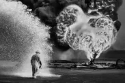 Chemical sprays protect this fire fighter against the heat of the flames.　Greater Burhan, after the Gulf War. Kuwait, 1991.(C) Sebastiao Salgado　