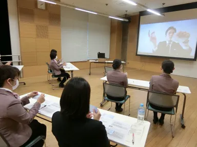 スクリーンに講師を映し出し、実践的なサービスのコツを伝授