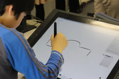 「Wacom Cintiq 21UX ペンタブレット」でデータをスケッチする子ども
