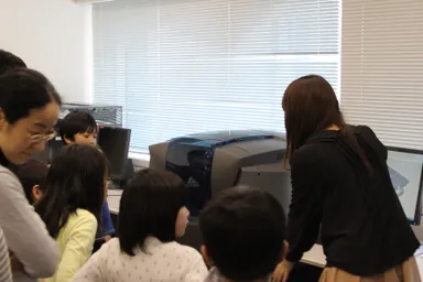 3Dプリンタの説明を受ける子どもたち