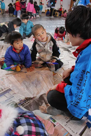 大学生から凧の作り方を聞く子供たち。