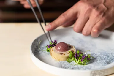味わい深い百日鶏の詰め物。卵黄に見立てて丸く仕上げた紅玉リンゴの赤ワイン煮ピュレをのせ、香味野菜を添えます。