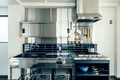 ステンレスの業務キッチンを入れた使い勝手の良いキッチン。奥には洗濯スペース。