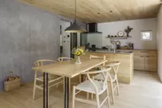 ナラ無垢材のキッチンやダイニングテーブルが、独特の素材感を持つグレーの塗り壁とマッチ