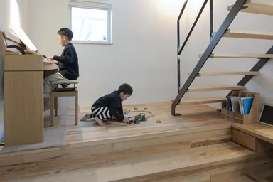 二段上がった「ステージリビング」で長男はピアノの練習、弟はおもちゃ遊び