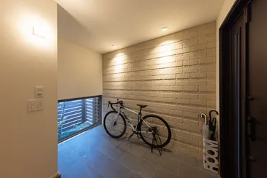 アクセントタイルが張られた玄関の地窓からは木陰がのぞく