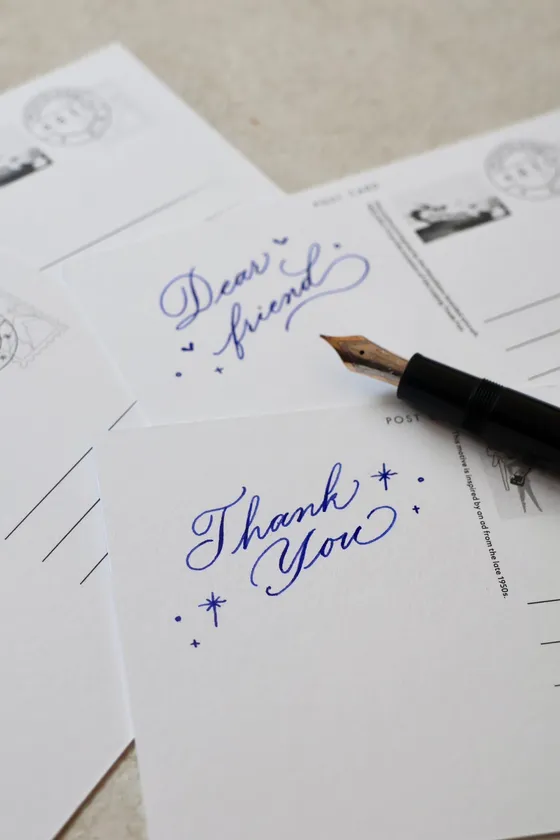 カリグラファーがポストカードに一言書き添えます