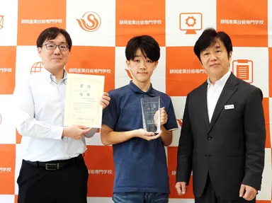 写真は、優勝に輝いた静岡産業技術専門学校(SANGI)みらい情報科2年生、堀池 凌空さんと、塩崎先生と校長の佐藤先生