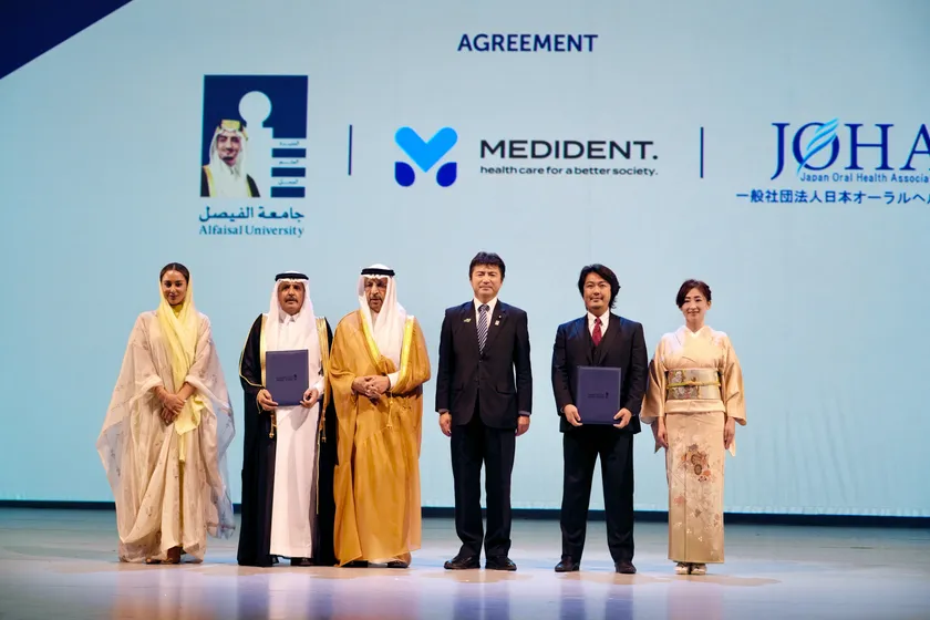 「大阪・関西万博『日・サウジEXPO投資フォーラム』壇上での調印。左から:アルファイサル大学・ヌール・A・アル・サアドゥーンセンター長、アルファイサル大学ムハンマド・Ali・アル・ハイアザ学長、サウジアラビア王国ハーリド・アル=ファーレフ投資大臣、古賀友一郎経済産業副大臣、メディデント代表 富田大介、一般社団法人日本オーラルヘルス協会富田由美子理事」