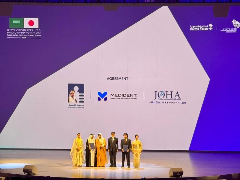 会場スクリーンに表示された提携3者のロゴ(Alfaisal University/MEDiDENT/日本オーラルヘルス協会)。公式プログラムとして壇上で合意。