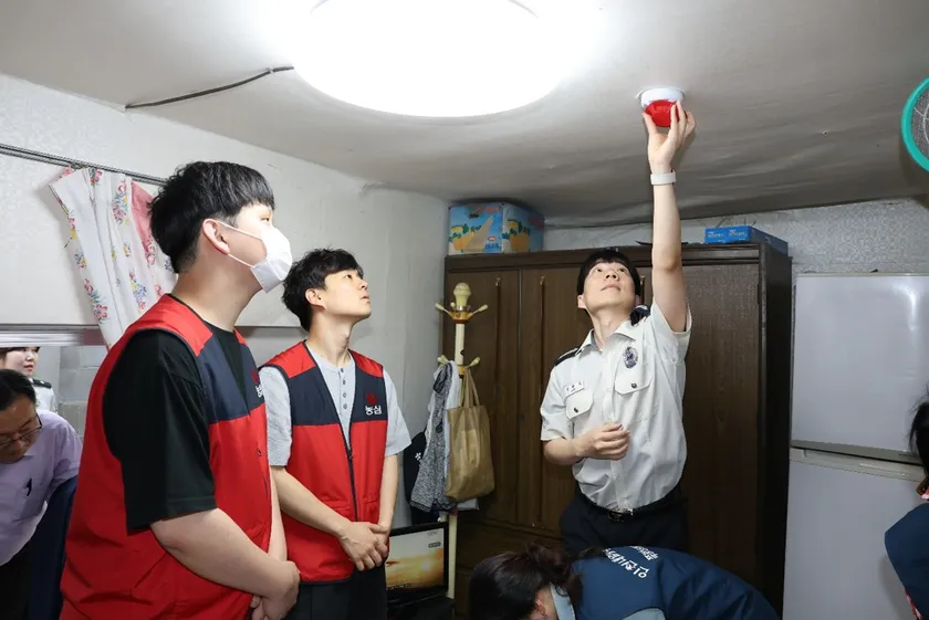 キャンペーンで配布された火災報知器を取り付ける農心社員と消防庁職員