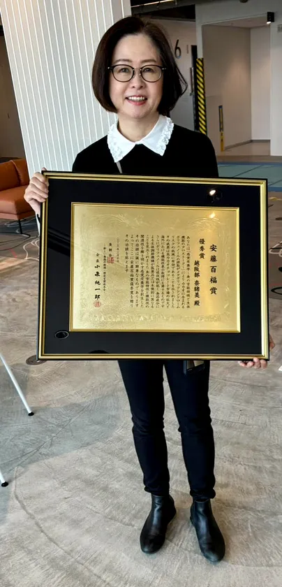 賞状を掲げる越阪部 奈緒美教授