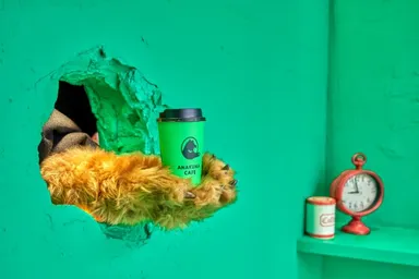 緑色の壁に開いた穴からモフモフのクマの手が商品を提供します