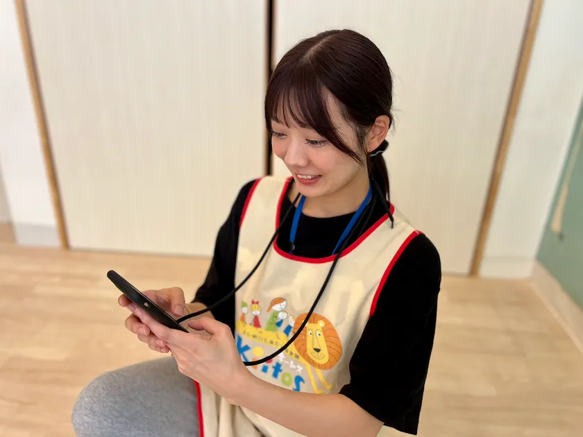 スマートフォンで園児情報を確認する保育士