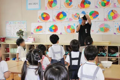 スタッフがうどん作りの工程を実演し、興味深そうに見学する園児たち
