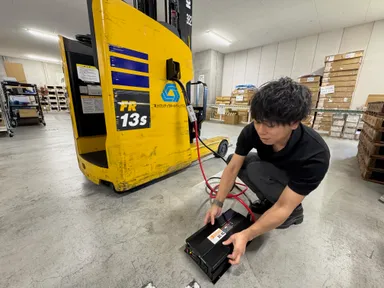 倉庫内で稼働する電動フォークリフトからインバータを介し電源を取り出す様子