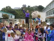 浜松城を背景に「金の出世小判うちわ」を持った浜松の子供たちと成功祈願