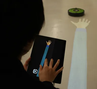 掃除ロボットへ向けて手を伸ばす